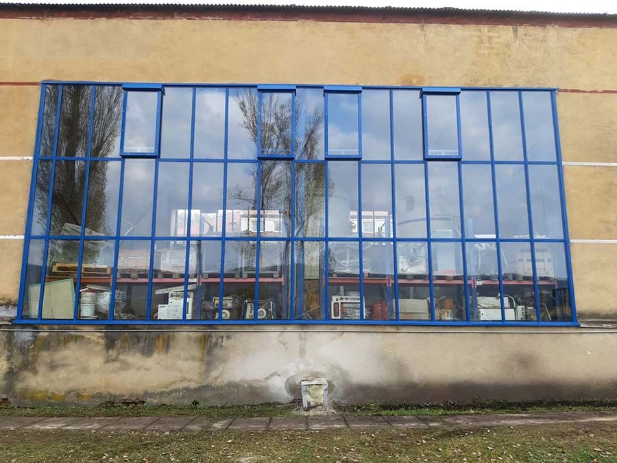 Prosklená stěna v modrých rámech na starší hale