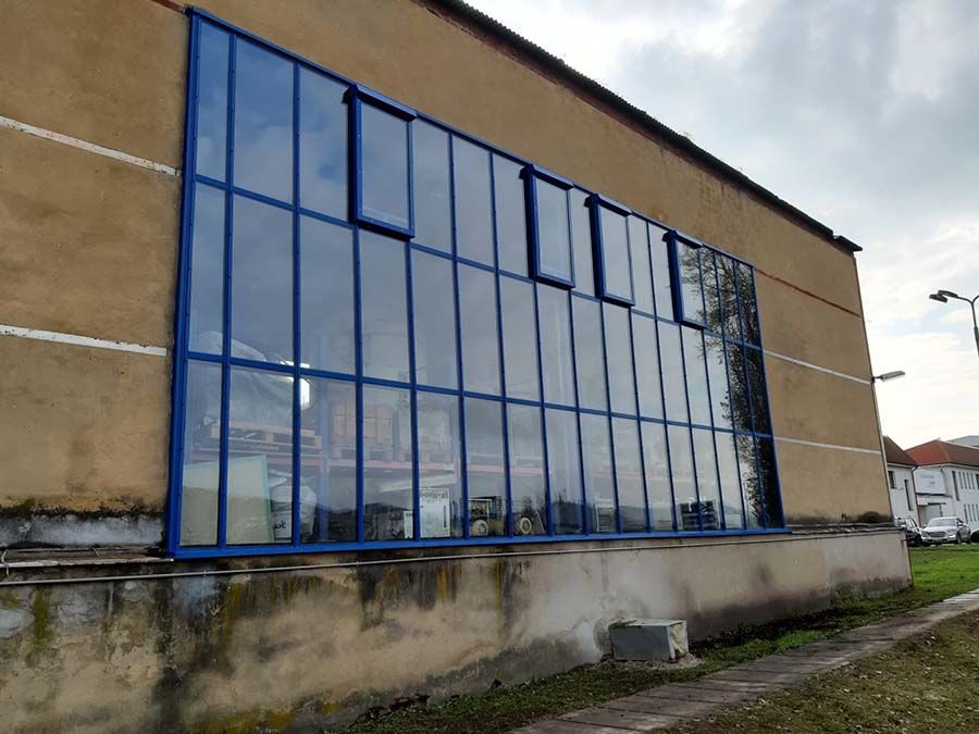 Prosklená stěna v modrých rámech se třemi výklopnými okny