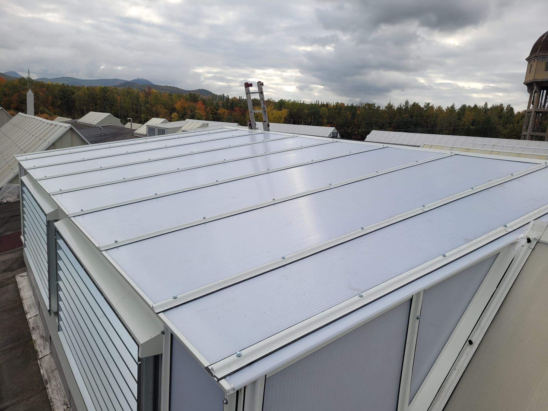 Polykarbonátové zastřešení lucernové nástavby, na střeše opřený žebřík