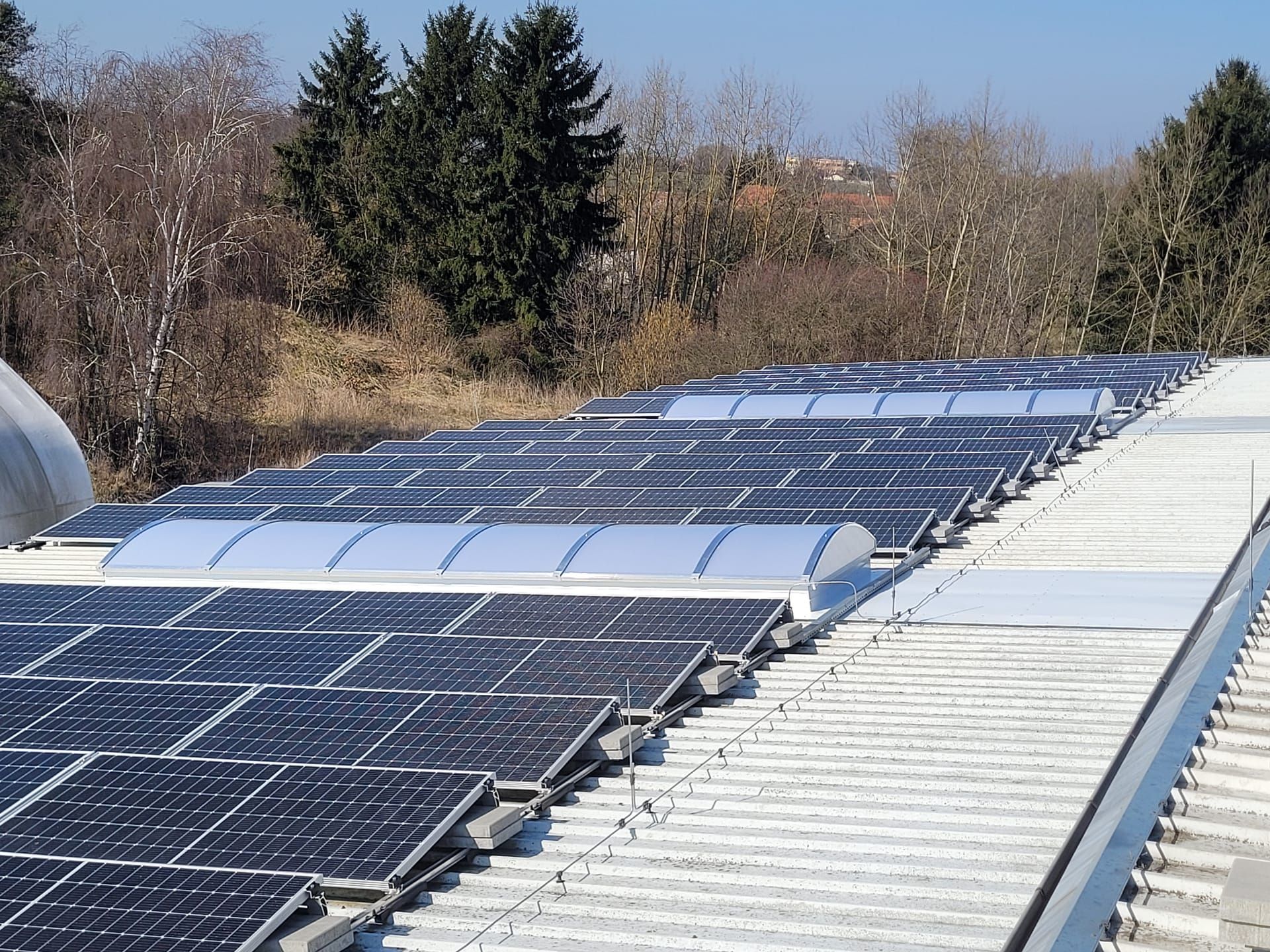 Řada obloukových světlíků mezi fotovoltaickými panely na střeše