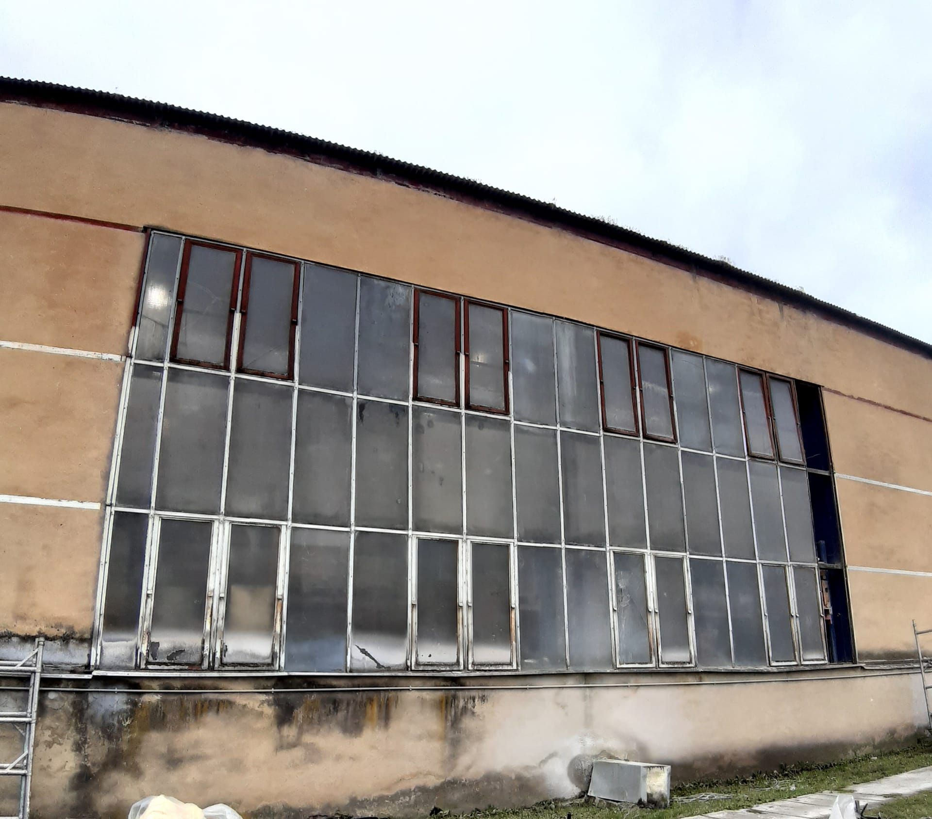 Původní prosklená stěna haly se zašlým zasklením a starými rámy před výměnou