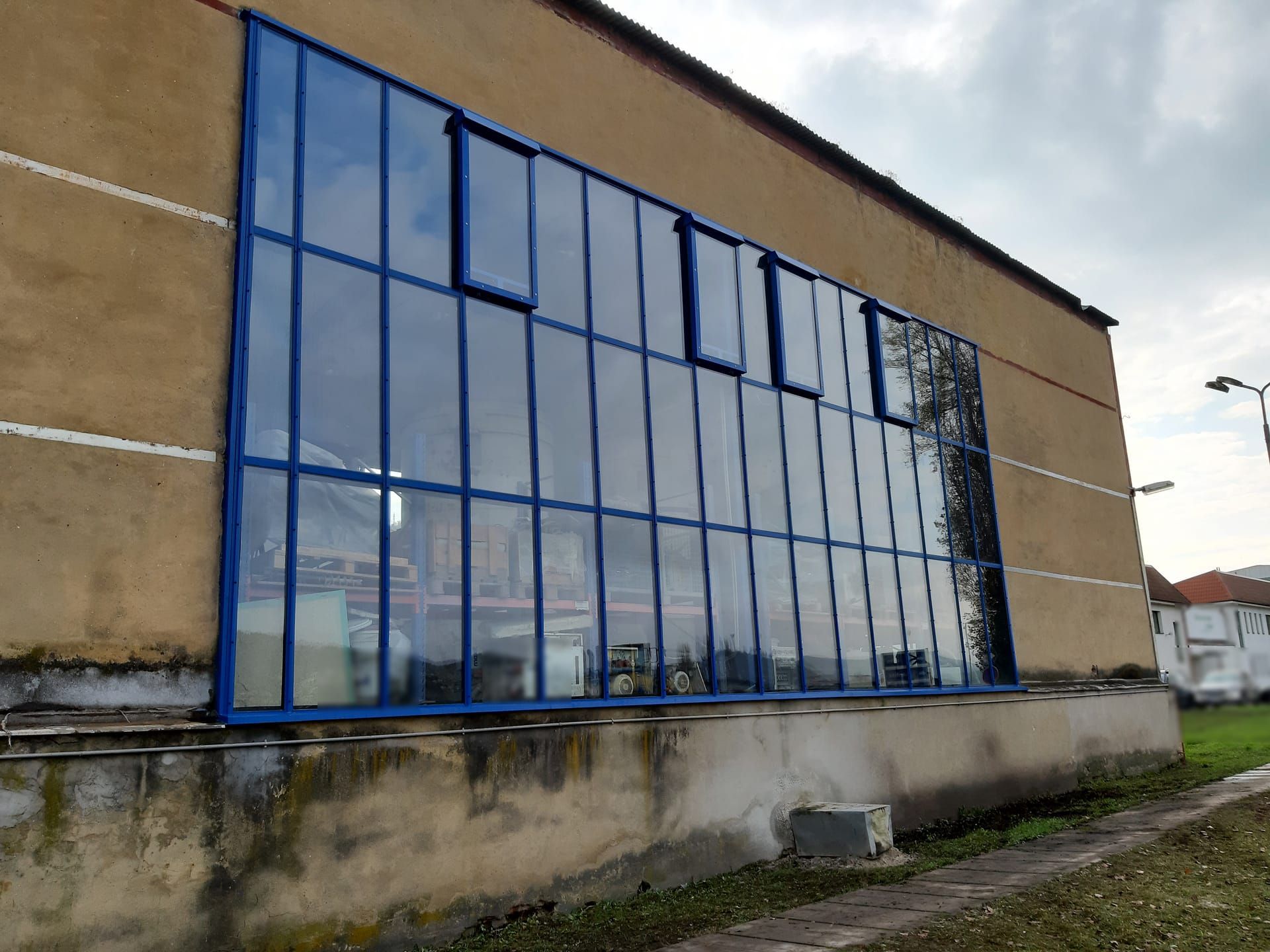 Nová prosklená stěna s modrými rámy při pohledu zešikma