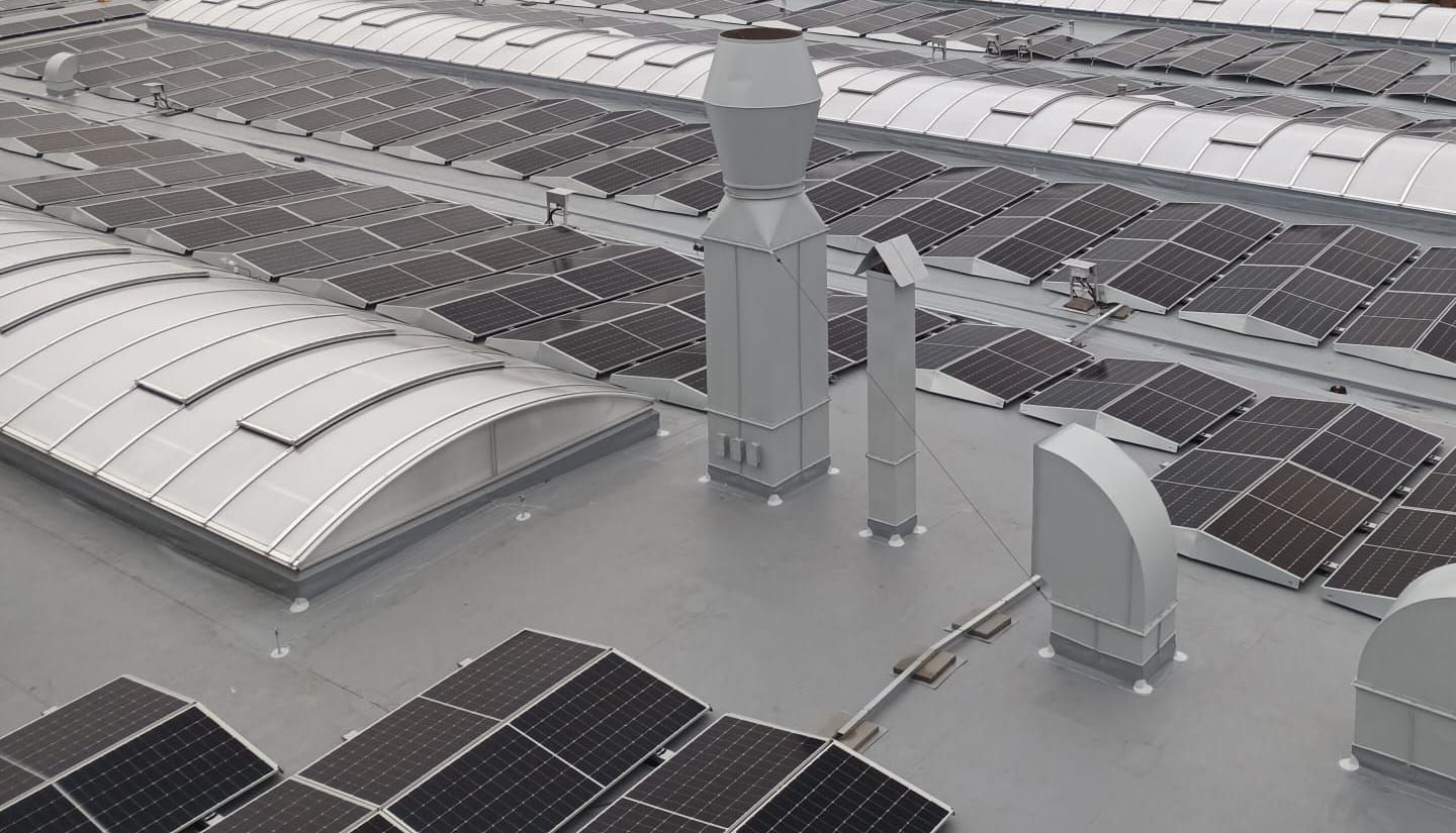 Obloukové světlíky mezi fotovoltaickými panely a vzduchotechnickými komíny na ploché střeše