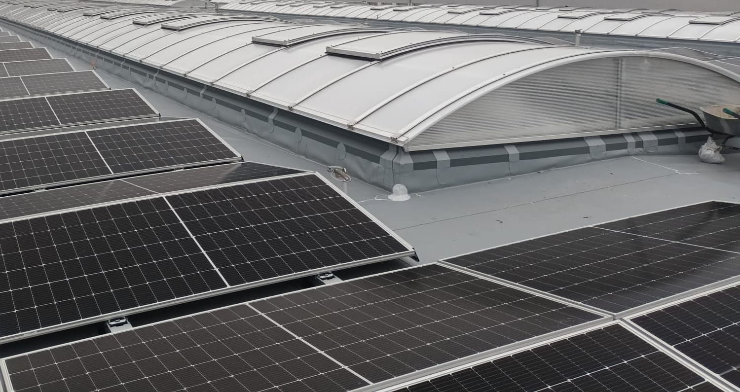 Detail obloukového světlíku s oplechovaným lemem a fotovoltaickými panely v popředí